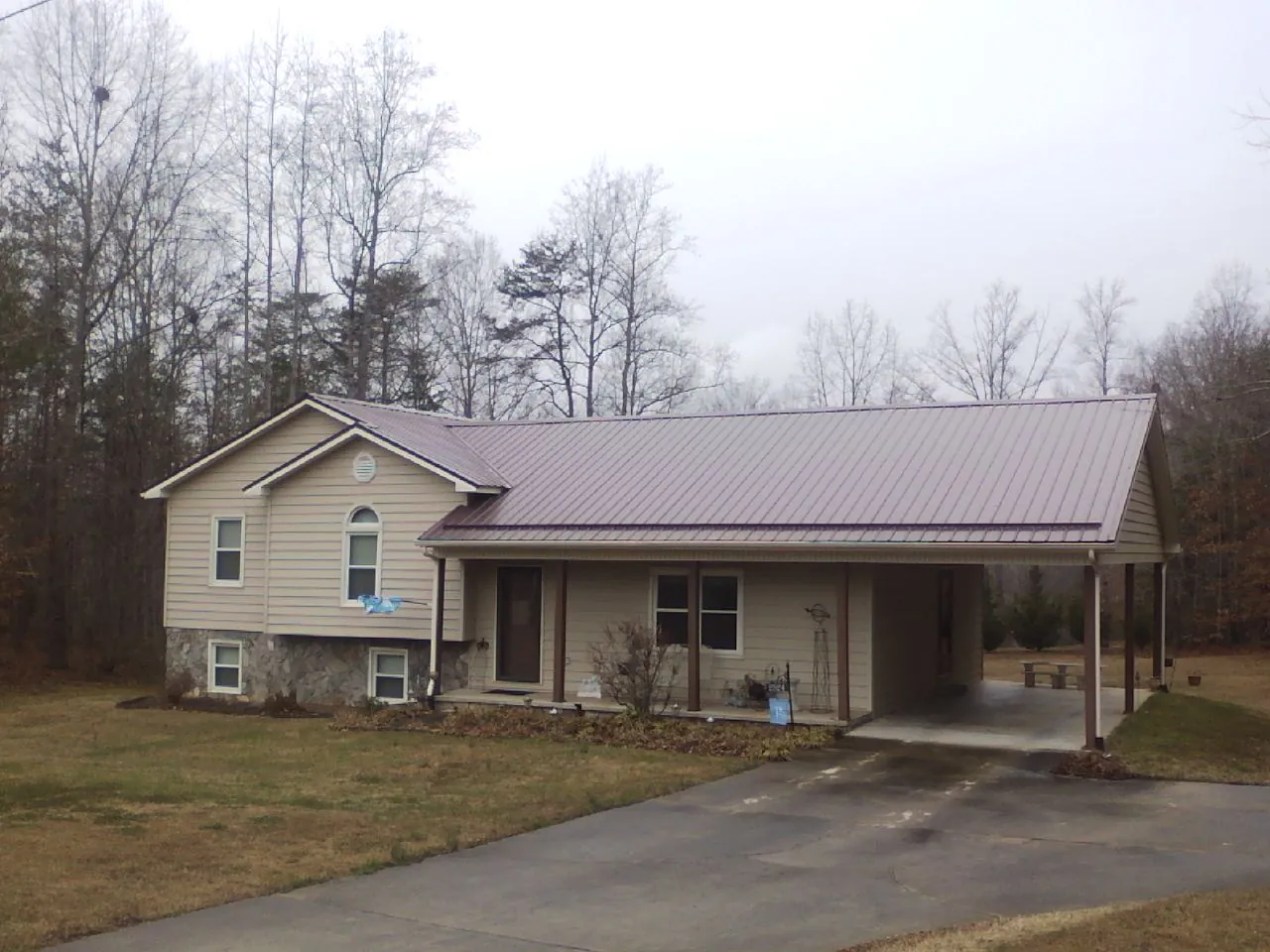 Burgundy metal roof on a tan split level home with an attached carport in Westwego