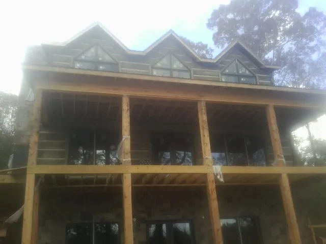 Dormers and porch framing on a large log home under construction — Roof Coating work by our crew in Westwego