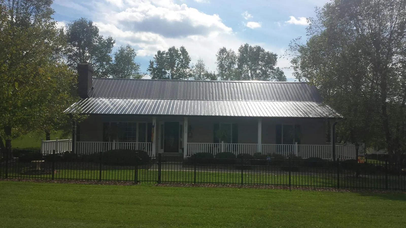 Gray metal roof on a brick ranch with a full width front porch — Gutter Guard Installation work by our crew in Westwego